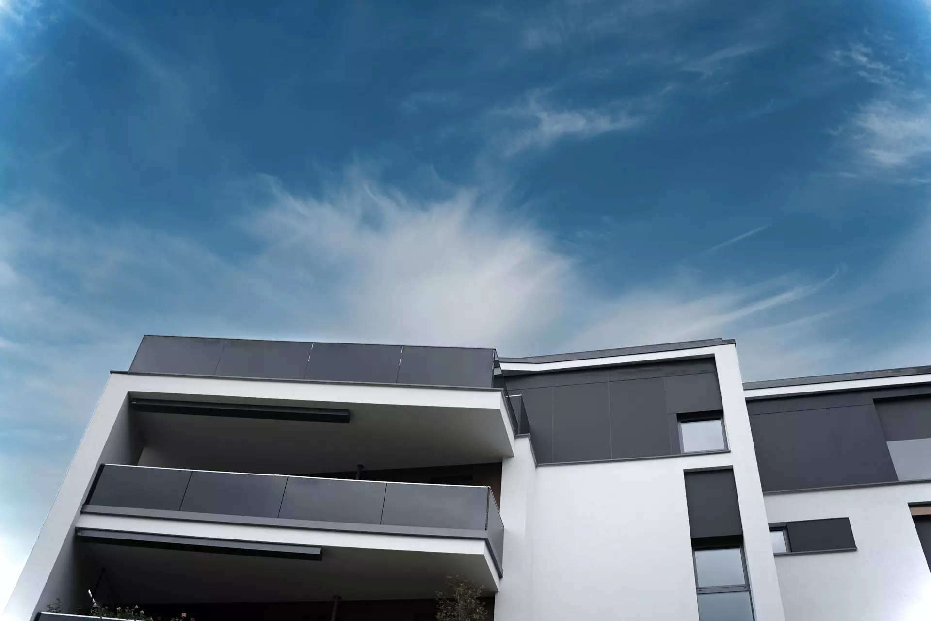 Detailaufnahme eines modernen Wohnhauses mit Balkon vor blauem Himmel