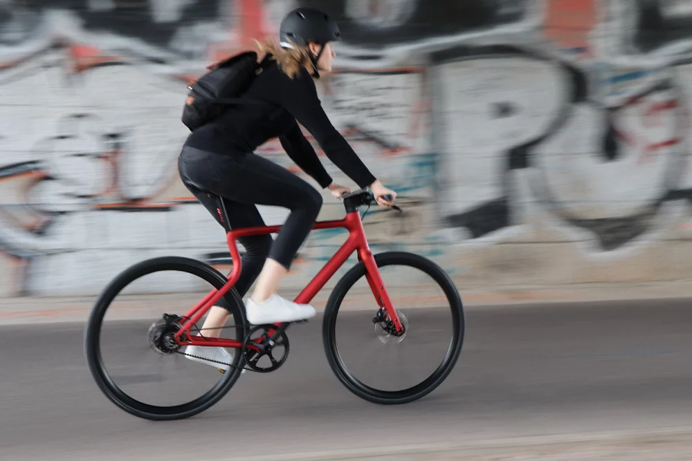 Seitenannsicht einer jungen Frau fahrend auf dem Urwahn Stadtfuchs E-Bike in Oxid 